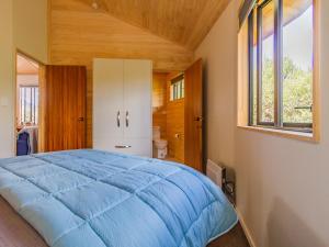 a bedroom with a blue bed and a window at The Snowglobe - Ohakune Modern Yurt Style Chalet in Ohakune