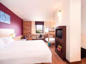 a hotel room with a bed and a tv at Ibis Bangkok Riverside in Bangkok