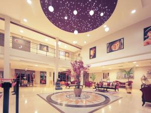 a lobby with a large lobby with chairs and a table at Mercure Cayenne Royal Amazonia in Cayenne