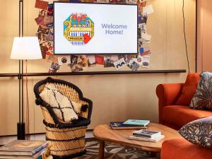 a living room with a welcome home sign on a screen at Mama Shelter Prague in Prague