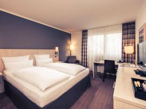 a hotel room with a large bed and a desk at Mercure Hotel Bielefeld Johannisberg in Bielefeld