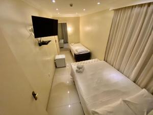 a hotel room with a bed and a flat screen tv at Lemes Hotel in Barra do Piraí