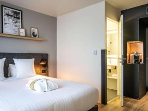 - une chambre avec un grand lit et des oreillers blancs dans l'établissement Hôtel Mercure Paris Gennevilliers, à Gennevilliers