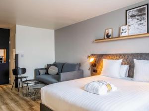 une chambre d'hôtel avec un lit et un canapé dans l'établissement Hôtel Mercure Paris Gennevilliers, à Gennevilliers