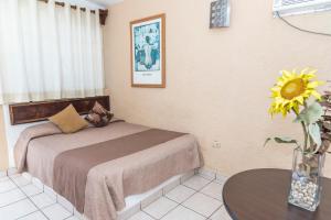 a bedroom with a bed and a vase with a sunflower at Hotel Villas Santa Ana in Boca del Río