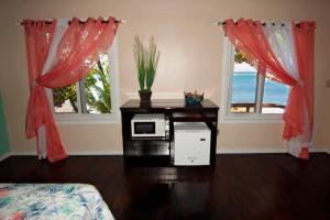 a room with a table with a microwave and two windows at Casita Océana in Sandy Bay