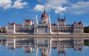un edificio del parlamento con su reflejo en el agua en Global Suites Budapest, en Budapest