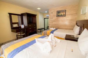 um quarto de hotel com duas camas e um espelho em Hotel Ambassador Mérida em Mérida