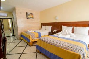 a hotel room with two beds and a balcony at Hotel Ambassador Mérida in Mérida