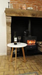 a table with a wine bottle and a glass in front of a fireplace at Gite No 16 in Châteauponsac