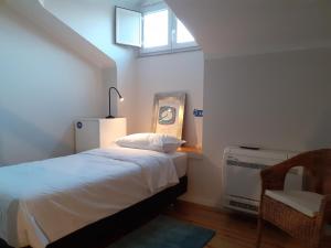 a bedroom with a bed and a window and a chair at Fonte Branca Guest House - Sé in Braga