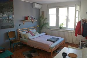 ein Schlafzimmer mit einem Bett und zwei Fenstern in der Unterkunft Atelier 22 in Belgrad