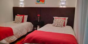 a bedroom with two beds with red and white at Alojamento Ar e Sol in Guimarães