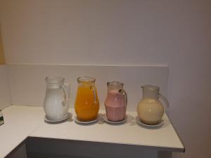 four different colored vases sitting on a shelf at Hotel Nadai in Mar del Plata