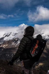 a person with a backpack standing on top of a mountain at Monkeywasi Climbing Hostel in Huaraz