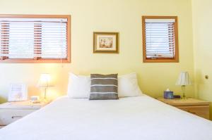 a bedroom with a white bed and two windows at Sea Treasures Inn in Seward
