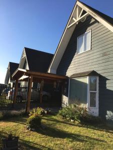 une maison avec une terrasse couverte à l'avant et une clôture dans l'établissement Quimantu, à Puerto Varas