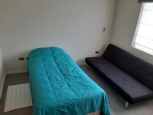 1 dormitorio con 1 cama azul y 1 sofá en Quimantu, en Puerto Varas