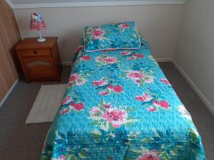 a bed with a blue comforter with flowers on it at Quimantu in Puerto Varas