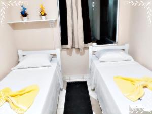2 Betten in einem Zimmer mit gelben Decken in der Unterkunft HOTEL CASTELINHO DE SOROCABA in Sorocaba