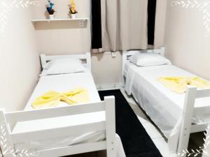 2 Betten in einem kleinen Zimmer mit gelber Bettwäsche in der Unterkunft HOTEL CASTELINHO DE SOROCABA in Sorocaba