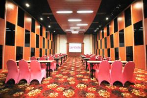 a conference room with tables and chairs and a screen at favehotel MEX Tunjungan Surabaya in Surabaya