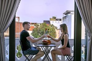 un uomo e una donna seduti a un tavolo su un balcone di Focus Homestay a Hoi An