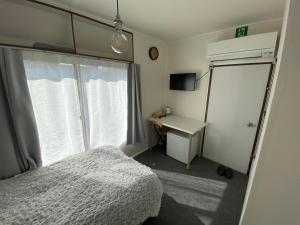 a bedroom with a bed and a desk and a window at CASA KUNISAKU in Machida