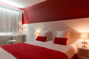 - une chambre rouge avec un lit et 2 oreillers rouges dans l'établissement Hôtel Central Parc Oyonnax, à Oyonnax