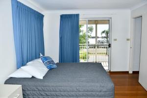 1 dormitorio con 1 cama con cortinas azules en Kalbarri Seafront Villas en Kalbarri