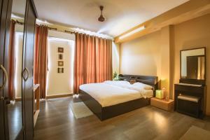 um quarto de hotel com uma cama e um espelho em The Pines Serviced Apartments em Patan