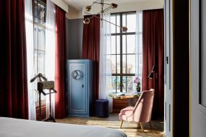 a bedroom with a bed and a chair and windows at Hotel Indigo The Hague - Palace Noordeinde, an IHG Hotel in The Hague