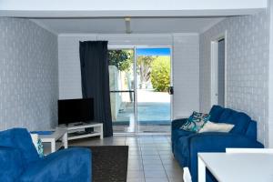 sala de estar con 2 sofás azules y TV en Kalbarri Seafront Villas en Kalbarri