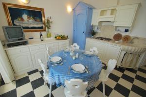 kuchnia z niebieskim stołem i krzesłami oraz telewizorem w obiekcie Vacanze Toscane In The Seaside w mieście Marina di Castagneto Carducci +34 zdjęcia