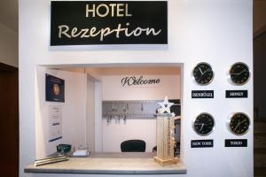 a hotel reception with clocks on a wall at Hotel Garni Haus Schönberger in Heiligenhaus