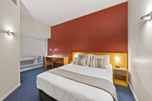 een hotelkamer met een groot bed en een bureau bij YEHS Hotel Melbourne CBD in Melbourne