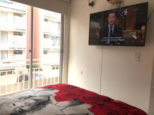 una camera da letto con TV a schermo piatto a parete di Cosmopolita Rojo a La Serena
