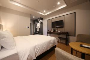 天安市The Mains Hotel的一间酒店客房,配有一张床铺、一张桌子和一台电视