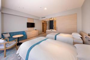 a hotel room with two beds and a television at Hotel Granvia Okayama in Okayama