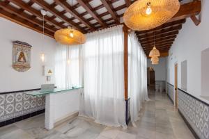 un corridoio con una grande finestra con tende bianche di BOHEMIA SANLUCAR a Sanlúcar de Barrameda