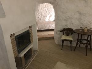 a living room with a fireplace and a table and a bed at Casa Cueva “La Estrella” in Granada