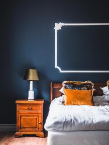 a bedroom with a blue wall and a bed and a nightstand at Weinbergs in Trelleborg