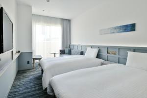 北谷町的住宿－Lequ Okinawa Chatan Spa ＆ Resort，酒店客房设有两张床和一台平面电视。