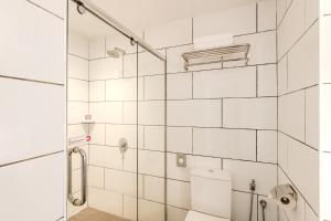 a white tiled bathroom with a toilet and a shower at FOX Lite DPulze Cyberjaya by Ascott in Cyberjaya