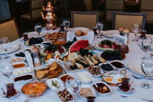 einen Tisch mit Teller mit Speisen und Weingläsern in der Unterkunft Misgibi Hotel in Bursa
