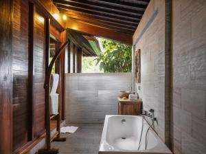een badkamer met een bad en een wastafel bij Secluded Jungle Villa in Ubud