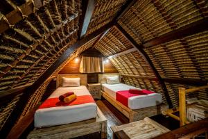 um quarto com 2 camas num quarto com telhado de palha em Kelapa Cottage em Amed