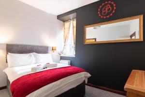 a bedroom with a bed with a red blanket and a mirror at Bazpackers in Inverness