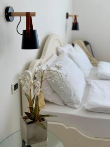 Arcovacanze في آركو: سرير بمخدات بيضاء وطاولة مع مصباح