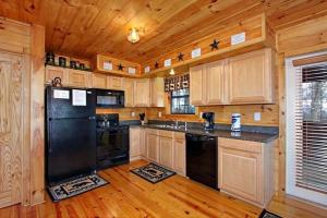uma cozinha com armários de madeira e um frigorífico preto em Secluded Memories Cabin em McCookville